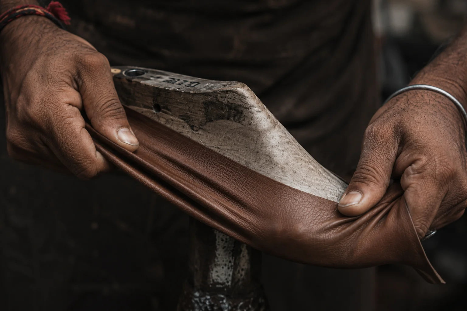 Artisan shaping leather over a wooden last by hand