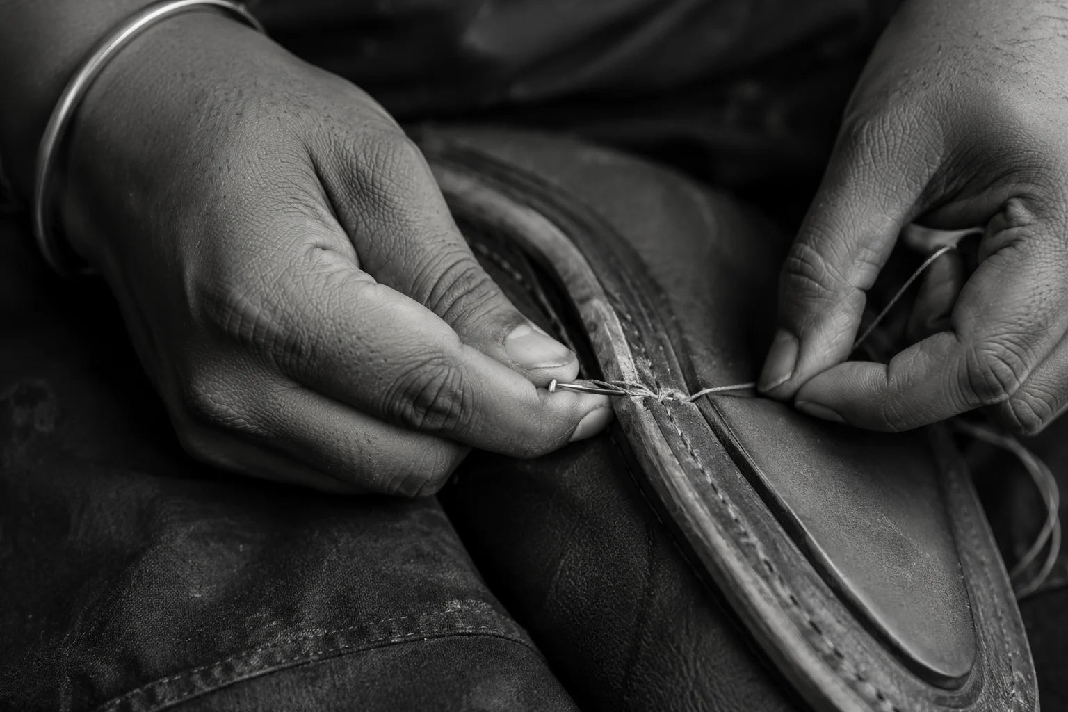 Hands hand-stitching the welt of a leather shoe